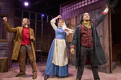 Desperate Measure-Jail Johnny Blood, wearing a long brown duster, brown chaps, and red vest with his fist up; and a triumphant expression Susana wearing a blue and white novice nun dress with fist swinging and uncertain expression; and Sherrif Green in black duster, burgundy embroidered vest, black pants, and holding up his black brimmed hat with exultant expression. In the bakground are the jail's barred cell and a wood wall with a window and a door.